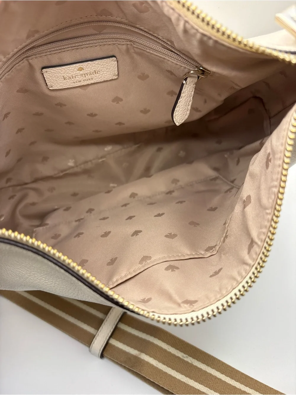 Kate Spade New York cream leather crossbody bag featuring a striped webbing Stra